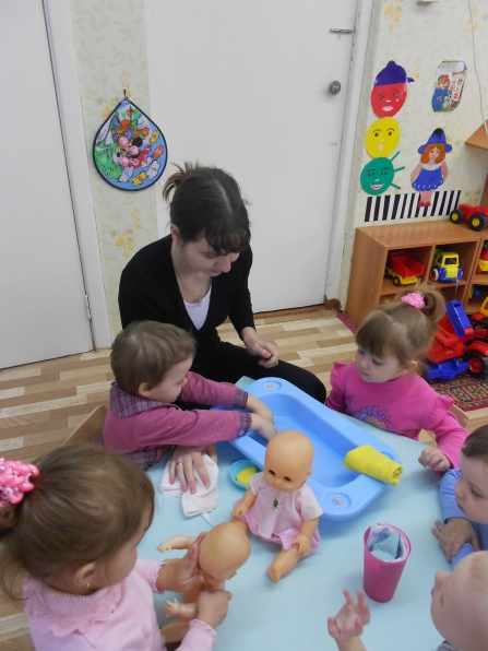 Children and teacher bathe dolls