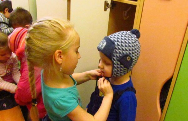 Girl helping little boy put on his hat
