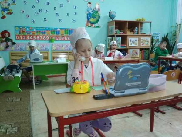 A girl in a doctor&#39;s costume sits in front of a small netbook
