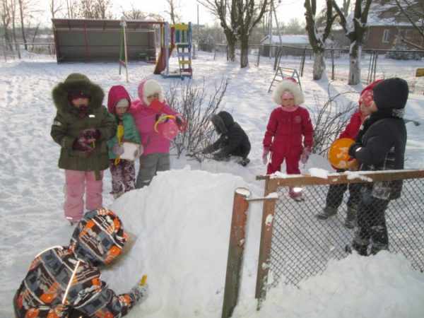 Preschoolers play with snow on a walk