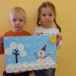 Мальчик и девочка держат аппликацию со снеговиком