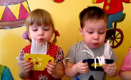 Boy and girl blowing on paper crafts