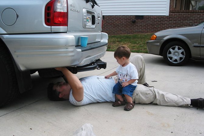 Baby watches dad fixing car