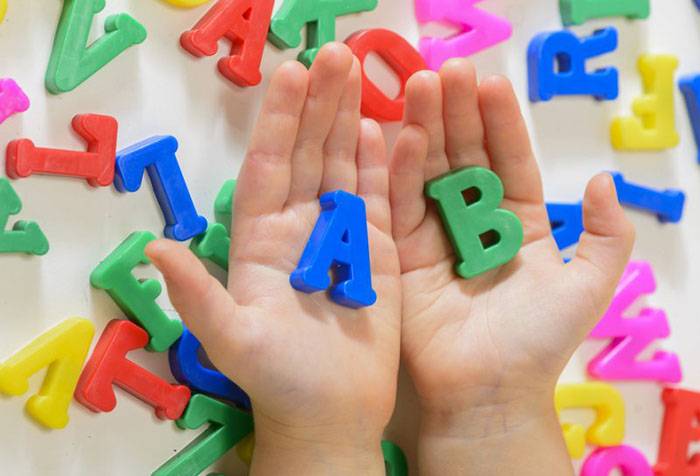 Ребенок держит буквы английского алфавита