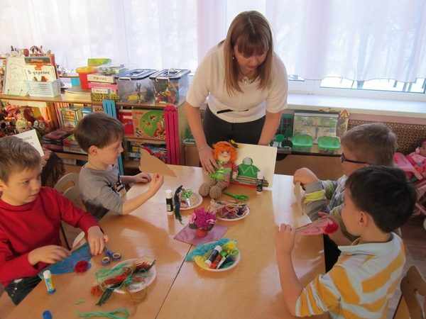 A teacher with a toy in her hand explains a task to children